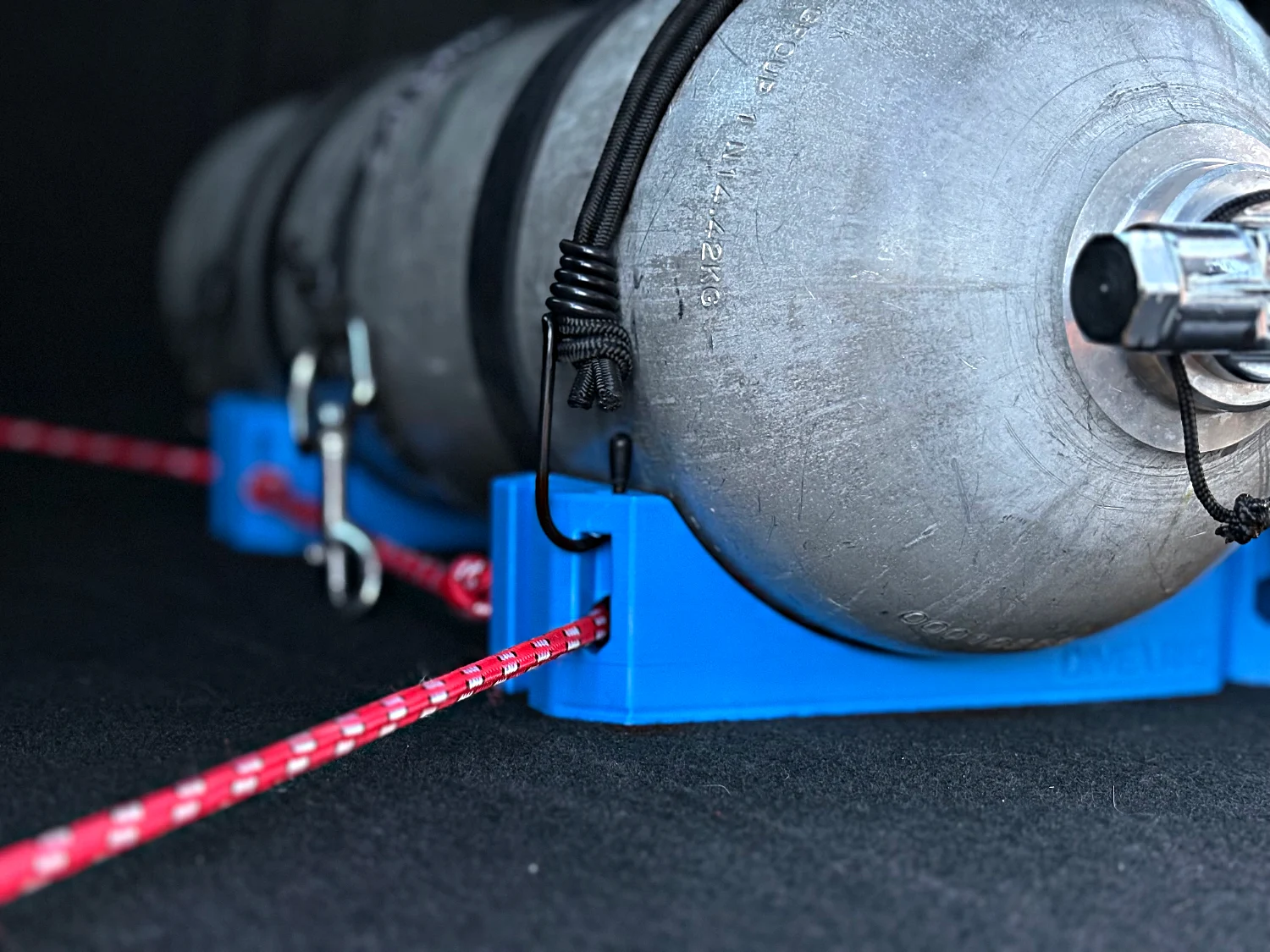 Bungee hooked into the square nest of the end block, red line running to the floor anchor