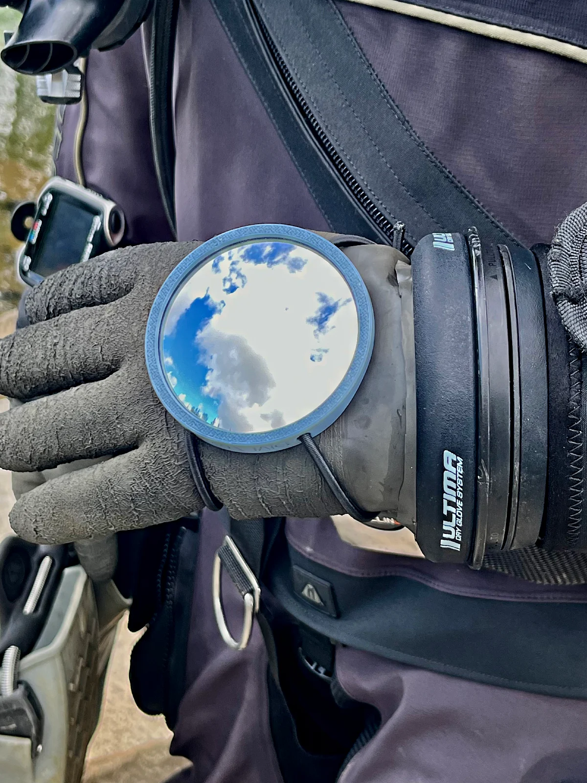 The Mirror 75 on the back of the hand, drysuit and harness in frame
